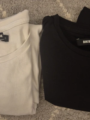 2-pack basic t-shirts från Bik Bok - Två klassiska basic t-shirts från Bik Bok i storlek S. Ena t-shirten är vit och den andra är svart, båda med rund halsringning och i mjuk bomull. Perfekta att matcha till allt och superbekväma för vardagen.
