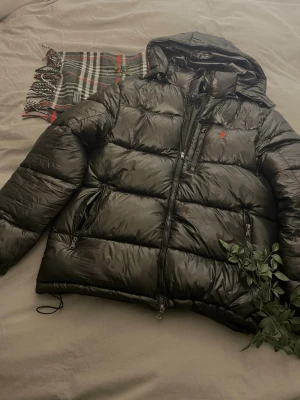 Svart pufferjacka från Polo Ralph Lauren -  Kan ej garantera äkthet för att den ä köpt på Plick. Qr funkar och den ä i fint skick. Jag vill ej ha någon krångel med retur och så. Jackan är i barn xl vilket passar bra till s för en lite mer baggy fit och för m till en normal fit. Skriv gärna vid minsta lilla fundering 