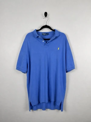 Vintage Polo Ralph Lauren Piké L Royalblå Blå 100% Bomull Polo Shirt Herr Y2K - • Storlek: L • Färg: Klarblå • Passform: Classic Fit  • Krage: Klassisk pikékrage • Material: 100% bomull  Skick: Plagget är i väldigt fint skick med två mindre hål via ena armen och vid nederdelen. Eventuella anmärkningar anges alltid tydligt i beskrivningen och visas på bilderna.  Nypris: Cirka 1 500 kr.  📦 Skickas snabbt och packas omsorgsfullt. 💬 Hör gärna av dig om du har frågor eller vill se fler bilder. 🤝 Samfrakt erbjuds vid köp av flera plagg – kika gärna in mina andra annonser!• Storle