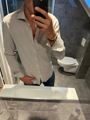 Beige-rutig skjorta från Boggi Milano  - Snygg beige och vit rutig skjorta från Boggi Milano i storlek M. Skjortan är i riktigt bra skick och har inga defekter. Jag är 188cm och bär strlk M vilket är lagom på mig. Hör av er vid fler frågor;)
