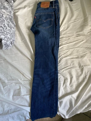 Levi's 511 mörkblå jeans W31 L34 - Säljer ett par klassiska Levi's 511 jeans i mörkblå denim. Modellen är slim fit med raka ben och fem fickor. Snygga kontrastsömmar och ikonisk läderpatch bak i midjan. Perfekta för en stilren och avslappnad look.