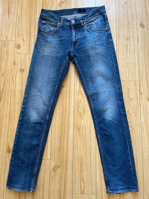 Blå jeans från Tiger of Sweden - Snygga blå jeans från Tiger of Sweden med klassisk femficksmodell och raka ben. Jeansen har en lätt tvättad look med subtila slitningar och kontrastsömmar. Perfekta för dig som gillar stilrena och tidlösa jeans i denim.
