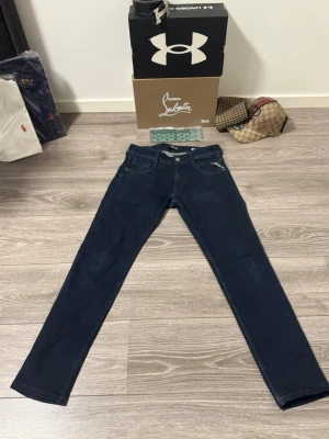 Replay jeans - Storlek: W28 L32.                                             Snygga mörkblå slim fit jeans med klassisk femficksdesign och raka ben. Jeansen har silverfärgade nitar och knapp, samt kontrastsömmar. Perfekta för en trendig och avslappnad stil. Materialet ser ut att vara denim med stretch för extra komfort.