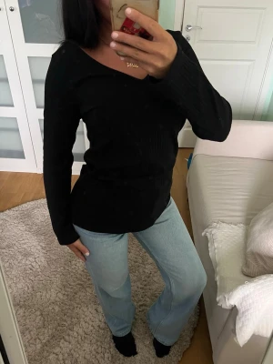 Svart ribbad långärmad topp - Svart långärmad topp med v-ringning och ribbad struktur. Toppen har en smickrande passform och är perfekt att styla med jeans eller kjol. Materialet är mjukt och stretchigt.