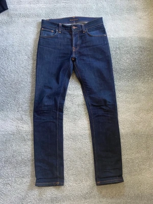 Nudie jeans grim Tim  - Ett par riktigt snygga marinblåa jeans från Nudie i storlek 31/32. Han på bilden är 179. Modell Dry true navy. Mycket gott skick, inga defekter. Har du några frågor? Fråga på