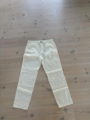 Vita linnebyxor HM - Snygga vita linnebyxor med avslappnad passform och resår i midjan. Byxorna har raka ben, sidofickor och en enkel knappstängning framtill. Perfekta för en chill och stilren look under varma dagar.