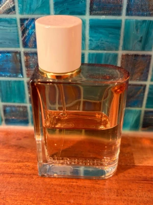 Burberry Intense, edp 30ml - Burberry Intense, og-versionen. Elegant parfym från Burberry i en stilren, rektangulär glasflaska med vit kork och gulddetalj. Doften har toppnoter av röda bär och björnbär, hjärtnot av jasmin och basnot av benzoin. Perfekt för dig som gillar fruktiga och blommiga dofter. Ca 50% kvar i en 30ml-flaska.