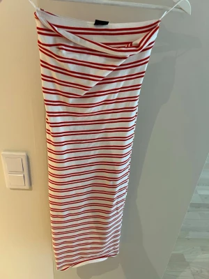 Randig klänning från Gina Tricot - Säljer en vit och röd randig klänning från Gina Tricot i storlek XS. Klänningen är ärmlös och har en kroppsnära passform med smala axelband. Perfekt för sommardagar och enkel att styla med sneakers eller sandaler.