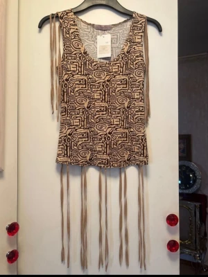 Vintage linne - Superfint mönstrat linne / debardeur i modellen "Santiago" från märket Jad. Snyggt grafiskt mönster i bruna och beigea toner. Fina fransar och faller vackert Strechig material  Helt ny, nypris 500kr