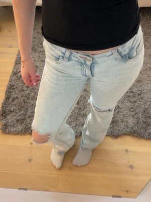 Blåa jeans med rosa brodering från Nelly  - Säljer ett par blåa jeans med rosa brodering baktill och är i st 36