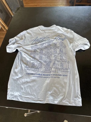 Ljusblå t-shirt med tryck - Vit t shirt med motiv på ryggen aldrig använd då jag gillade inte hur den satt då den är relaxed fit storlek S
