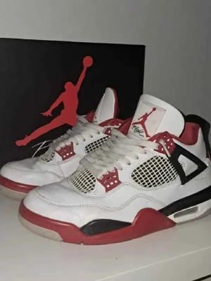 Air Jordan 4 Retro Fire Red sneakers - Säljer ett par Air Jordan 4 Retro Fire Red sneakers i vitt, rött och svart. Skorna har klassisk meshpanel, synlig Air-sula och ikoniska Jumpman-loggan på plösen. Perfekta för dig som gillar streetwear och vill sticka ut med en tidlös modell. Kan skicka mer bilder privat