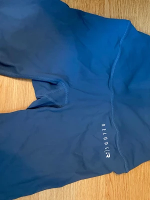 Blå träningsshorts från Relode - Snygga blå träningsshorts från Relode med hög midja och sömlös design. Tillverkade i stretchigt material som sitter skönt och formar sig efter kroppen. Perfekta för träning eller chill. Relode-logga tryckt på sidan.