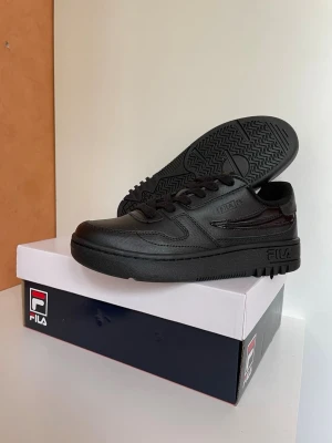 Svarta Fila sneakers i läder, stl 38 nya oanvända  - Stilrena svarta sneakers från Fila i lågt modellutförande. Skorna är tillverkade i slittåligt läder med matchande svarta skosnören och sula. Diskret Fila-logga på sidan och tungan. Perfekta för en clean och klassisk look. Stl 38
