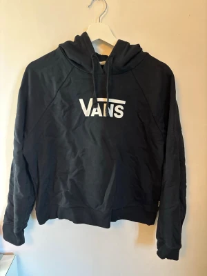Svart hoodie från Vans - Säljer en svart hoodie från Vans med vit logga på bröstet. Hoodien har huva med dragsko och långa ärmar. Tillverkad i mjukt material som passar perfekt för en avslappnad stil. Klassisk och enkel design som funkar till det mesta. Skulle säga att storleken är mer en S än en M.