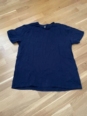 Mörkblå basic t-shirt - En enkel mörkblå t-shirt med rund hals och korta ärmar. Perfekt till jeans eller shorts för en clean och avslappnad look. Tillverkad i mjuk bomull som känns skön mot huden.