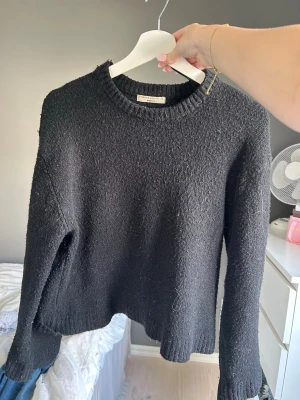 Svart stickad tröja från Gina tricot - Mysig svart stickad tröja med rund halsringning och långa ärmar. Tröjan har en enkel, rak passform och ribbstickade muddar vid ärmslut och nederkant. Perfekt för lager på lager och passar till det mesta i garderoben. Den är lite sliten i ena armen men inget som syns när den är på!