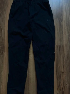 Svarta mjukisbyxor från Under Armour - Säljer ett par svarta mjukisbyxor från Under Armour. Byxorna har en relaxed fit med resår i midjan och diskret logga på låret. Perfekta för chill dagar eller träning. Materialet känns mjukt och följsamt.