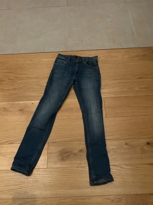 Blå slim jeans med klassisk tvätt - Säljer ett par blå slim fit jeans med klassisk tvätt och femficksmodell. Jeansen har normal midja och raka ben, tillverkade i mjuk bomull med lite stretch för skön passform. Perfekta till sneakers eller boots.