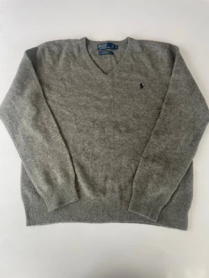 Grå stickad ulltröja från Ralph lauren - En stickad tröja från Ralph lauren i väldigt fint skick. Den är tillverkad i fårull vilket gör den perfekt nu till hösten. Hör av er vid funderingar!