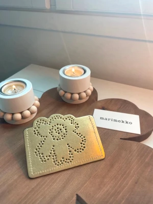 Marimekko Unikko Imprint card holder - Unused Marimekko Unikko Imprint gold-colored card holder. Length 10.5 cm, width 0.5 cm, height 8 cm. Surface material: leather. The Marimekko pouch shown in the picture is included.