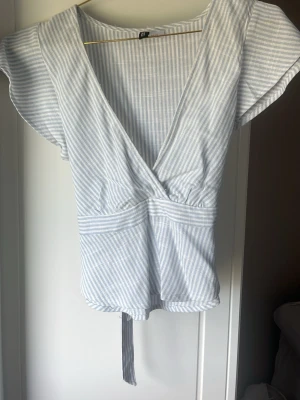 Randig topp med knyt i ryggen  - super söt och somrig topp/blus från hm. endast använd en gång, säljer för att den tyvärr är för liten. hör av er vid frågor! pris kan diskuteras