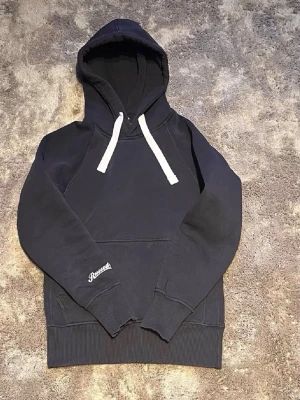 Russe hoodie mörkblå - Säljer en mörkblå hoodie från Russe med vita dragsnören i huvan och en stor magficka.  Perfekt för en chill och avslappnad stil. Hoodien är solblekt lite här och där och har lite slitningar längst ner vid på ärmen. Pris kan diskuteras! Skriv om du har frågor😃