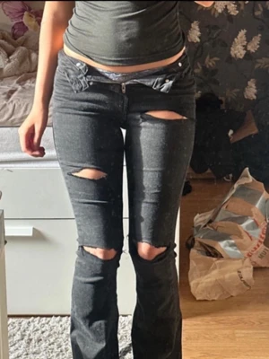 Svarta slitna jeans med hål - Säljer ett par svarta jeans med flera slitningar och hål på låren och knäna som jag har gjort själv💕Jeansen har låg midja, raka ben och klassiska fem fickor. Materialet är denim med stretch för extra komfort