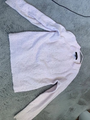 Ljusrosa stickad tröja Vero Moda - Mysig ljusrosa stickad tröja från Vero Moda. Tröjan har rund halsringning, långa ärmar och ribbade muddar vid ärmslut och nederkant. Perfekt för lager på lager och enkel att matcha med jeans eller kjol.