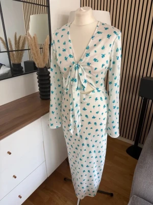 Vit långklänning med blå blommor från Gina Tricot  - Slutsåld klänning från Gina-tricot i storlek 32, men passar även mig som är 34. Aldrig använd, prislapp kvar. Orginal pris 599kr 