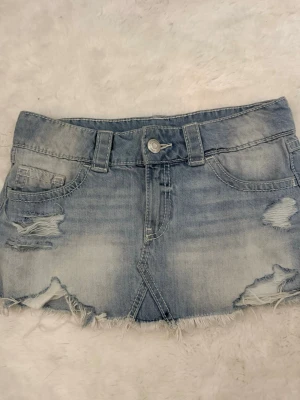 Ljusblå jeanskjol med slitningar - Säljer en kort ljusblå jeanskjol med slitna detaljer och rå kant ifrån Gina Tricot. Kjolen är aldrig använd och därav i väldigt fint skick. Väldigt populär kjol då den är slutsåld i de mesta butiker och helt online, strl S ( skriv till mig ifall du är intresserad )