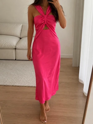 Rosa långklänning med twistad topp - Snygg rosa långklänning med twistad topp och cut-out detalj framtill. Klänningen är ärmlös och har en figurnära passform som framhäver siluetten. Perfekt för dig som vill sticka ut med en färgstark och trendig look.