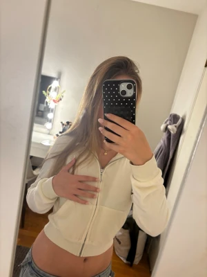 Vit croppad hoodie med dragkedja - Säljer en vit croppad hoodie från juicy couture med mjukt material med dragkedja framtill och fickor. Hoodien har huva med snören och ribbade muddar vid ärmslut och nederkant. Perfekt till jeans eller mjukisbyxor för en chill look.Original pris: 1200kr💞💞