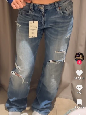 Blå slitna baggy jeans - Virala Zara jeans! Lågmidjade baggy jeans med slitningar. Finns ej att köpa längre på hemsidan💕(inte mina bilder) skriv för mer info. HÖGSTA BUDET JUSST NU ÄR 500kr