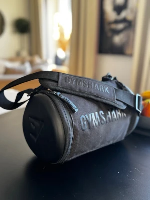 Liten träningsväska - Mindre tränings Väska från Gymstark. Endast testad hemma och är därför i mycket fint skick. Säljes då den inte kommer till användning.  Katt finns i hemmet, produkten rollas av så gott det går.