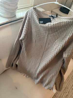 Beige långärmad blus med struktur - Säljer en beige långärmad blus med vågig struktur och avslappnad passform. 