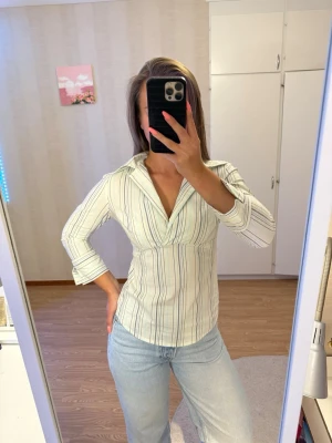 Veromoda Randig blus med v-ringning - Snygg blus med ljus bas och tunna ränder i blått, grönt och grått. Jag har storlek 34-36 men blusen är 38 och den sitter jättebra på mig 