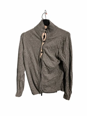 Libero Milano Kashmir Zip Cardigan – Grå – Strl 46 - Elegant grå zip cardigan från Libero Milano, köpt i butik i Milano. Kashmir-modell i storlek 46 med hög ribbad krage, dragkedja framtill och snygga knappdetaljer på insidan. Väldigt stilren italiensk design som fungerar både uppklätt och casual.  Fint skick.  📦 Skickas snabbt 💬 Skriv vid frågor eller för mått 👕 Fler märkesplagg finns på min profil – paketpris vid köp av flera