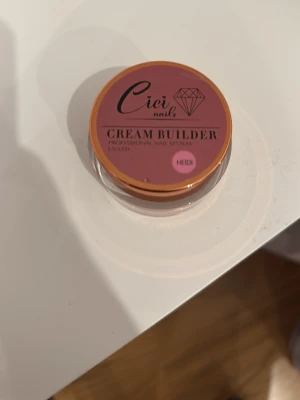 Cici Nails Cream Builder Heidi - Cici Nails Cream Builder i färgen Heidi är en professionell UV/LED builder gel för naglar. Gelen har en mjuk rosa ton och kommer i en rund burk med skruvlock. Perfekt för att bygga och forma snygga naglar med salongskänsla hemma. 30g använt kanske 15g 