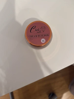 Ciei Nails Cream Builder Baby Pink - Bygggele för naglar i färgen Baby Pink från Ciei Nails. Kommer i en rund burk med skruvlock och har en krämig konsistens som passar perfekt för att bygga och forma naglar. Färgen är en mjuk, ljusrosa ton som ger ett fräscht och naturligt intryck. 15g