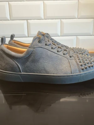 Grå mockasneakers med nitar - Snygga grå sneakers i mocka med coola nitar framtill på tån. Skorna har lågt skaft, matchande grå snörning och en stilren design som sticker ut. Insidan är ljusbeige och sulan är i samma grå ton som ovandelen. Perfekta för dig som vill ha något unikt. Hör av dig vid frågor🤗
