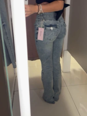 Blå bootcut jeans  - Säljer ett par blå bootcut jeans med silverdetaljer och knappar på bakfickorna. Jeansen är köpta på missäy men finns inte kvar att köpa hos dom, skriv för fler bilder. Jeansen är i väldigt bra skick 