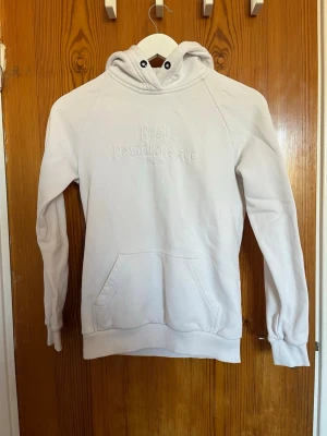 Vit hoodie från Peak Performance - Snygg vit hoodie från Peak Performance med broderad logga på bröstet. Klassisk modell med huva och känguruficka framtill. Perfekt för en avslappnad och stilren look.