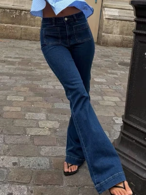 Mörkblå bootcut jeans med fickor - Säljer ett par mörkblå bootcut jeans med stora fyrkantiga framfickor och hög midja. Jeansen har en klassisk knappgylf och är tillverkade i denim med lätt stretch. Är lite slitna där nere men är förutom det som nya! Säljer då dom tyvärr blivit för små för mig 🥰 Nypris är 500kr
