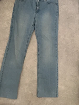 Ljusblå raka jeans - Säljer ett par ljusblå jeans med rak passform och klassisk femficksdesign. Jeansen har normal midja och är tillverkade i denim med en lätt tvättad look. Perfekta för en avslappnad och trendig stil.