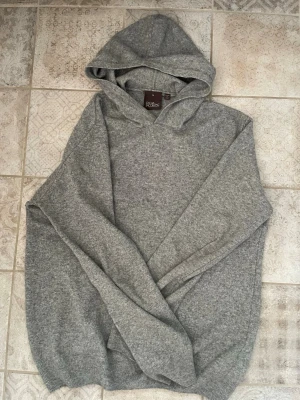 Grå stickad hoodie från Oscar Jacobson kashmir - Grå kashmir huddi från Oscar Jacobson, skön huddi som passar till alla outfits, stil ren tröja som passar perfekt när hösten börjar närma sig