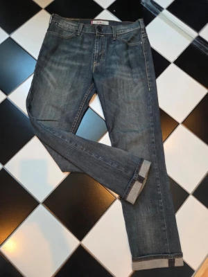 Vintage Levi's 519 - Klassiska blå jeans från Levi's med raka ben och uppvikta benslut. Jeansen har fem fickor, diskreta slitningar och den ikoniska läderpatchen bak i midjan. Tillverkade i slitstark denim med en snygg tvättad look och kontrastsömmar.