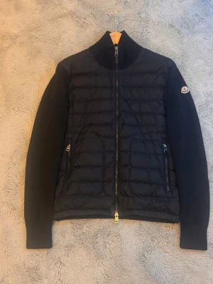 Moncler tricot cardigan S/xs - Säljer en moncler tricot cardigan som är köpt på merch Sweden, jag har orderbekräftelse och en returfraktsedel. Cardiganen är i Stl S men sitter som en xs. Skulle säga att den passar någon som är från 167-180 typ. Cardiganen har 1 halvt laga hål, ett litet hål på armbågen och ett litet märke längst ut på armen men annars är den i bra skick.  För fler bilder hör av er!