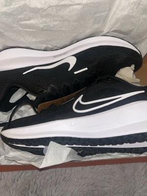 Nike svartvita sneakers/köparskor - Snygga svartvita sneakers från Nike med klassisk vit swoosh på sidan. Skorna har en låg siluett, svart mesh- och textilöverdel samt vit och svart sula med bra grepp. Perfekta för dig som gillar sportig och stilren look.