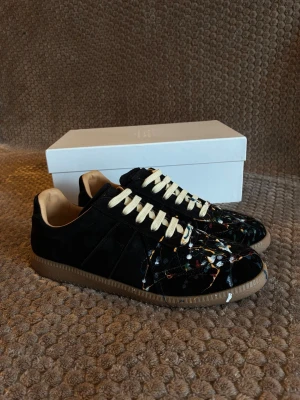 Maison margiela gats - Ett par svarta Maison Margiela gats med färgstänk i storlek 43. Säljer då dom tyvärr var för små for mig. kvitto finns! Tveka inte på att höra av dig vid frågor eller prisförslag! Fraktar samma dag!
